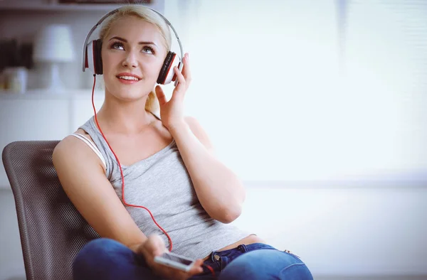 Jonge mooie vrouw thuis zitten op de bank en luisteren muziek — Stockfoto