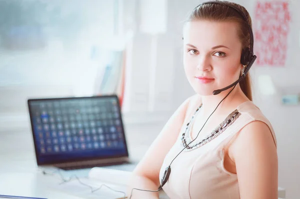 Mulher de negócios bonita trabalhando em sua mesa com fone de ouvido e laptop — Fotografia de Stock