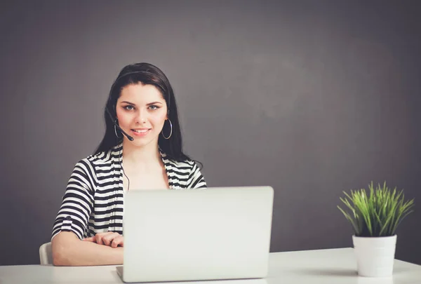 Mulher de negócios bonita trabalhando em sua mesa com fone de ouvido e laptop — Fotografia de Stock