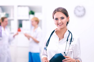 Kadın doktor elinde steteskopla hastanede duruyor.