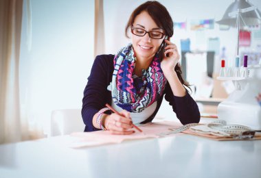 Genç terzi kâğıt üzerinde kıyafet deseni tasarlıyor.