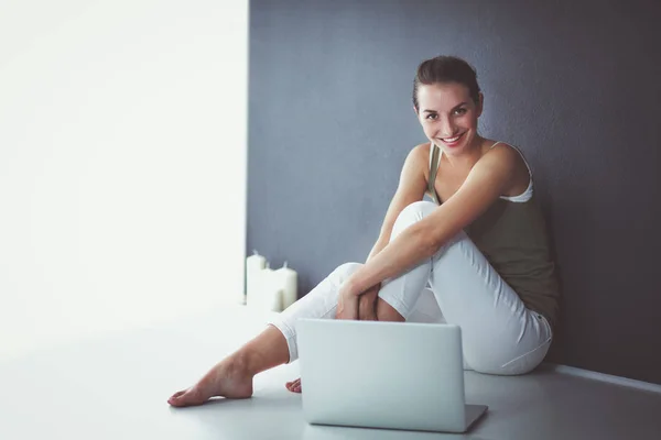 Attraktiva kaukasiska flicka sitter på golvet med laptop — Stockfoto