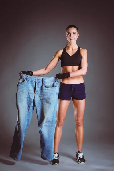 Ung fitness kvinna visar att hennes gamla jeans — Stockfoto