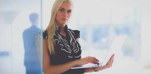 Молода бізнес-леді тримає ноутбук, стоячи в офісі — стокове фото
