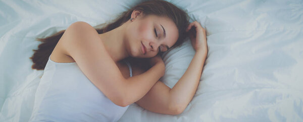 Beautiful young woman lying in bed comfortably and blissfully