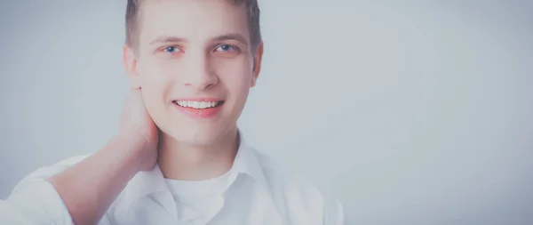 Portrét mladého muže s úsměvem, sedí na šedém pozadí — Stock fotografie