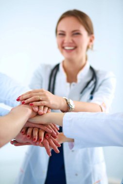 Doktorlar ve hemşireler tıbbi bir ekipte el ele tutuşuyorlar.