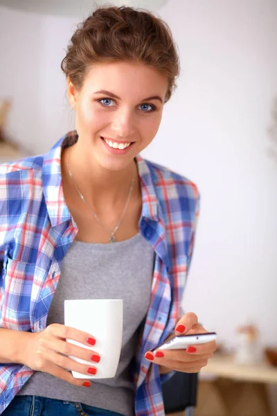 Usmívající se žena drží svůj mobil v kuchyni — Stock fotografie