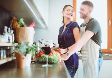 Bir çift evdeki mutfaklarında birlikte yemek pişiriyor.