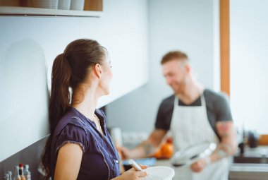 Bir çift evdeki mutfaklarında birlikte yemek pişiriyor.