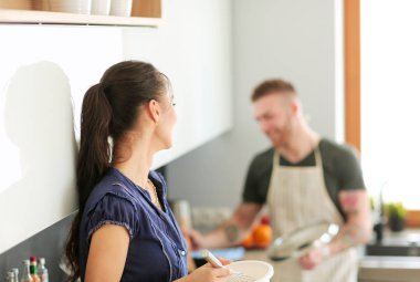 Bir çift evdeki mutfaklarında birlikte yemek pişiriyor.