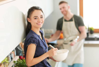 Bir çift evdeki mutfaklarında birlikte yemek pişiriyor.