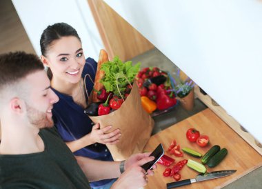 Mutlu çift Smartphone ayakta mutfakta kullanarak