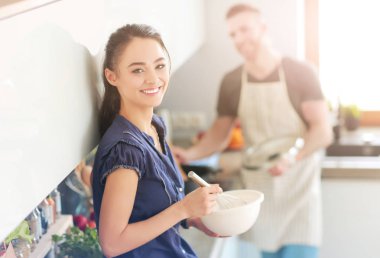 Bir çift evdeki mutfaklarında birlikte yemek pişiriyor.