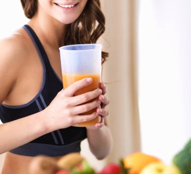 Mutfakta masada meyve suyu ve bardakla oturan bir kız.