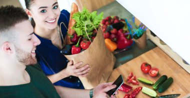 Mutlu çift Smartphone ayakta mutfakta kullanarak