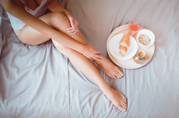 Mujer joven sentada en la cama con una taza de leche — Foto de Stock