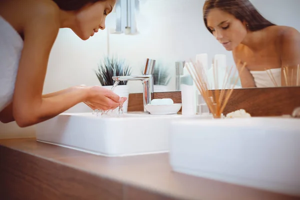 Jonge vrouw wassen haar gezicht met schoon water in badkamer — Stockfoto