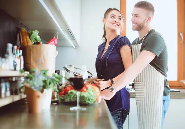 Bir çift evdeki mutfaklarında birlikte yemek pişiriyor.