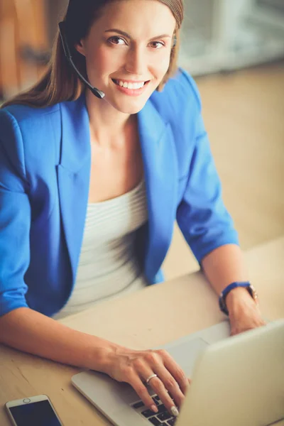 Portrait de belle femme d'affaires travaillant à son bureau avec casque et ordinateur portable. — Photo