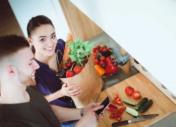 Gelukkige paar met smartphone staande in keuken — Stockfoto