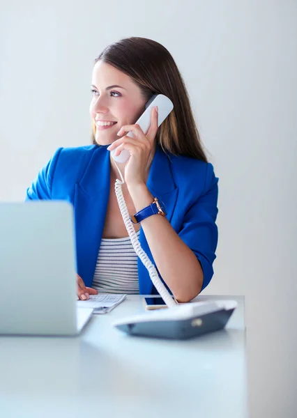 Portret van een jonge vrouw op telefoon achter een laptopcomputer — Stockfoto