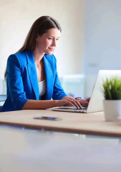 Kobieta siedząca na biurku z laptopem — Zdjęcie stockowe