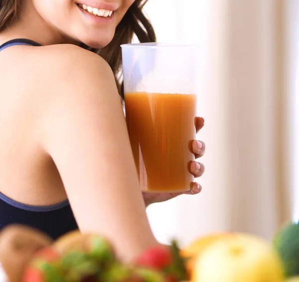 Chica sentada en la cocina en el escritorio con jugo de frutas y vasos —  Fotos de Stock