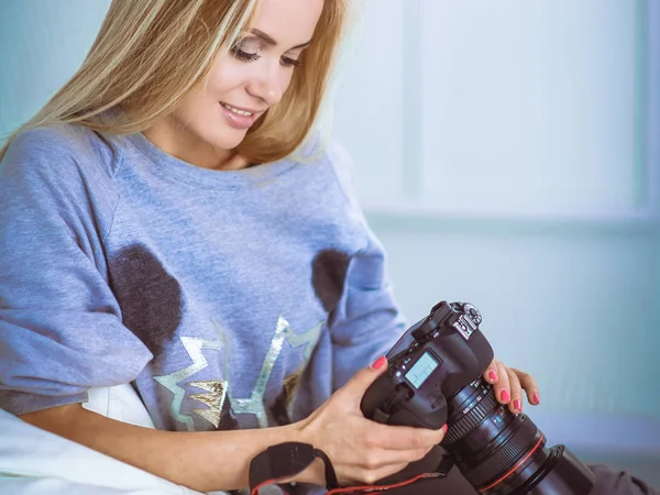 Kvinna sitter på en soffa i hennes hus med kamera — Stockfoto