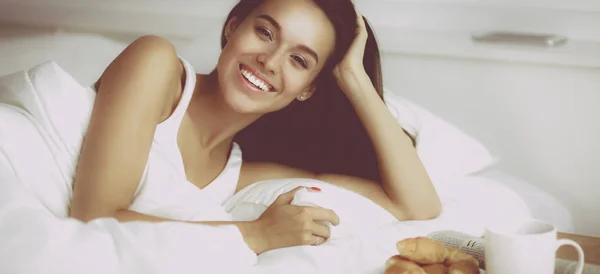 Mulher bonita sentada na cama e tomando café da manhã — Fotografia de Stock