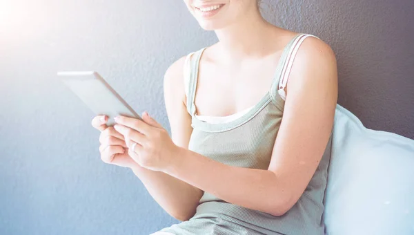 Aantrekkelijke Kaukasische meisje zittend op de vloer met cup en Tablet PC in de buurt van de muur — Stockfoto