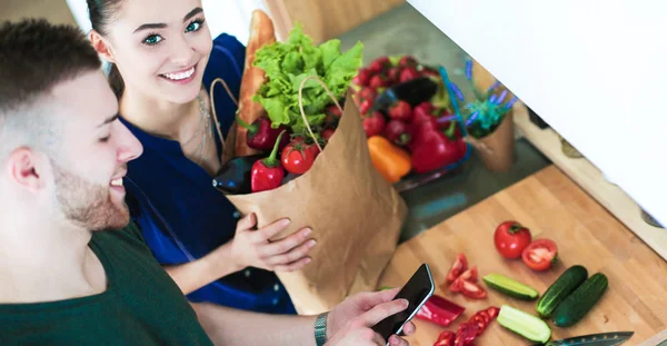 Mutlu çift Smartphone ayakta mutfakta kullanarak