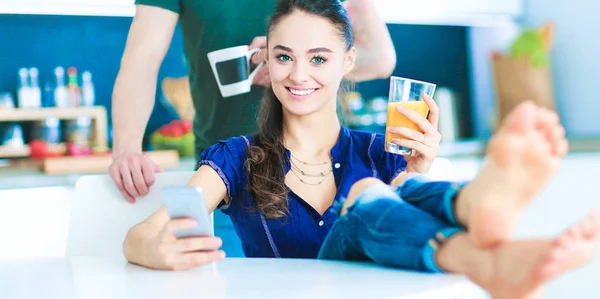 Pareja feliz usando smartphone sentado en la cocina — Foto de Stock