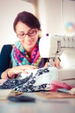 Çalışırken dikiş diken genç bir kadın. .