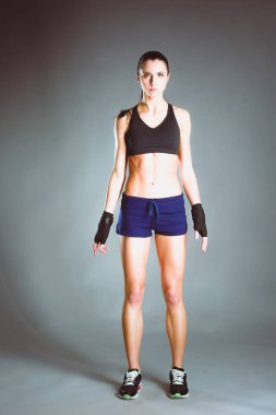 Spor giyim siyah arka plan karşı poz kas genç kadın.