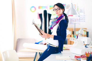 Güzel moda tasarımcısı stüdyoda duruyor. .