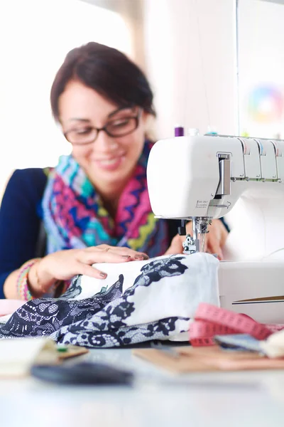 Young woman sewing while sitting at her working place . — Stock Photo, Image