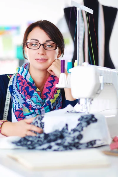 Mujer joven cosiendo sentado en su lugar de trabajo . — Foto de Stock