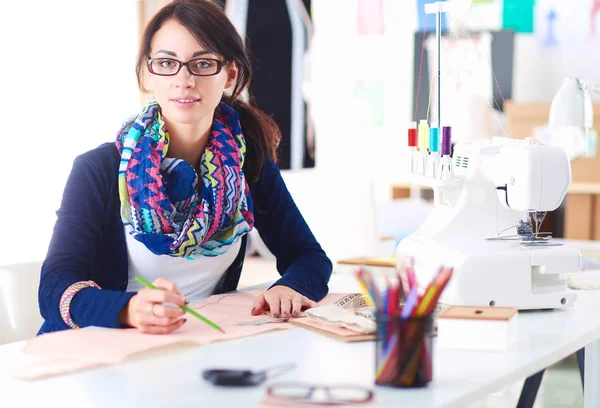 Bonito designer de moda sentado na mesa em estúdio . — Fotografia de Stock