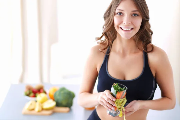 Mulher segurando um copo cheio de salada de frutas frescas com uma fita métrica ao redor do copo. — Fotografia de Stock