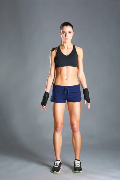 Musculosa joven posando en ropa deportiva sobre fondo negro . — Foto de Stock