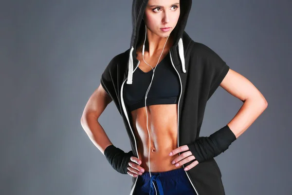 Muscular young woman posing in sportswear against black background — Stock Photo, Image