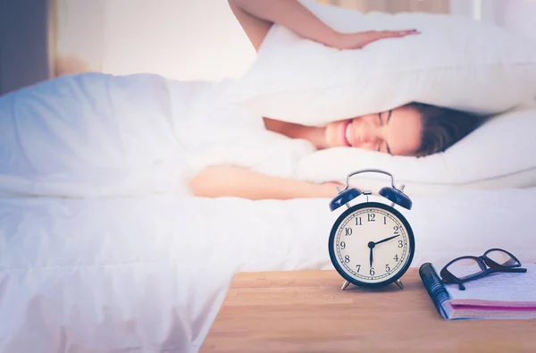 Una mujer joven apagando su despertador por la mañana. —  Fotos de Stock