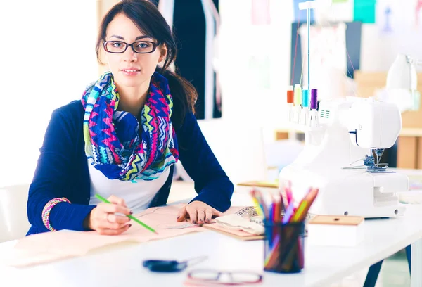 Bonito designer de moda sentado na mesa em estúdio . — Fotografia de Stock