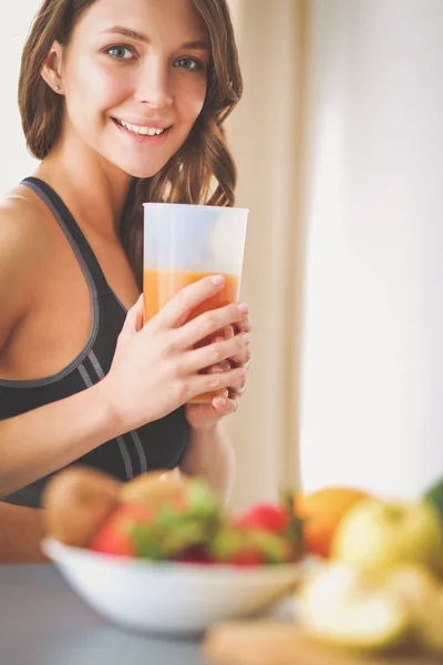 Flicka sitter i köket på skrivbord med frukt och glas med juice. — Stockfoto