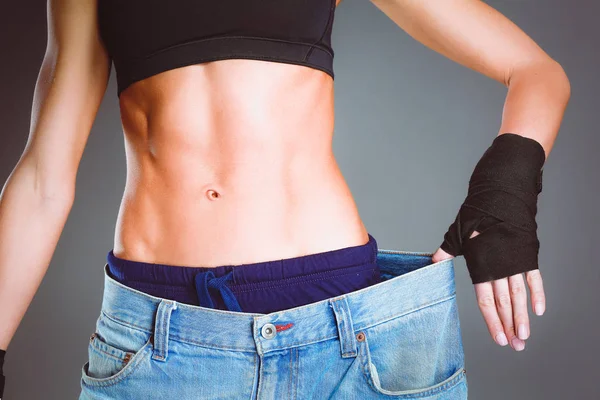 Young fitness woman showing that her old jeans . — Stock Photo, Image