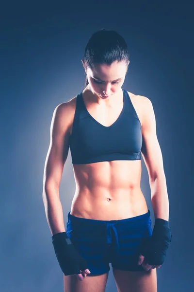 Muskulöse junge Frau posiert in Sportbekleidung vor schwarzem Hintergrund. — Stockfoto