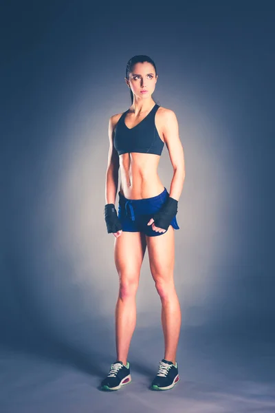Мускулистая молодая женщина позирует в спортивной одежде на черном фоне . — стоковое фото