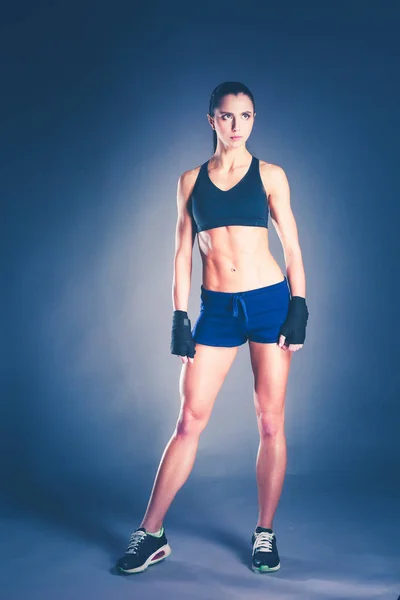 Musculosa joven posando en ropa deportiva sobre fondo negro . — Foto de Stock