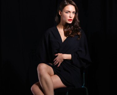 Siyah arka plan üzerine izole bir sandalye oturan güzel kadın